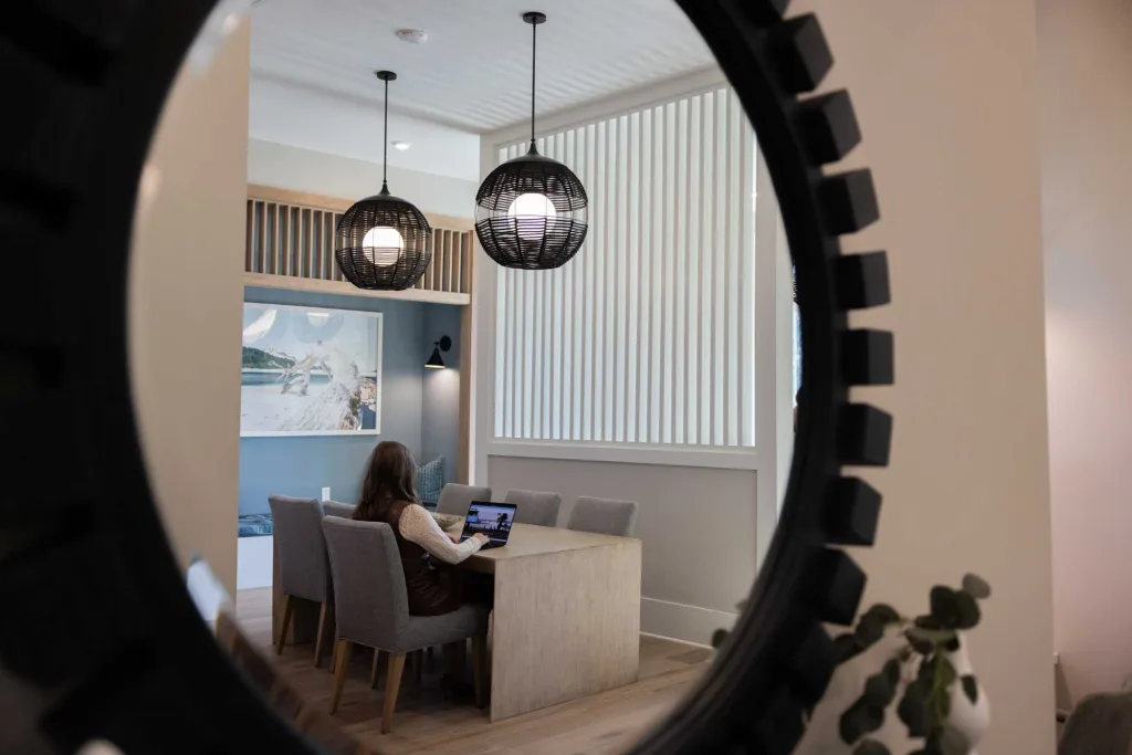Mirror showing reflection of a woman sitting at a table on a laptop