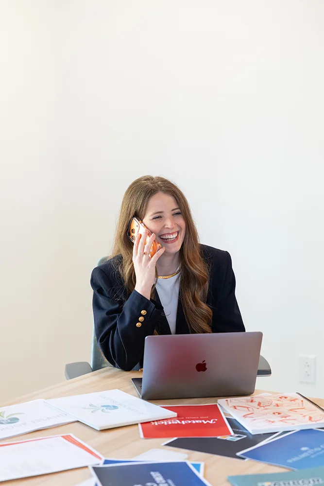 Olivia Rice, content strategist at Matchstick Social, talking on the phone sitting at a laptop